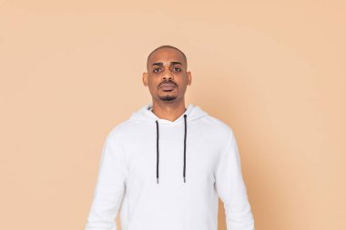 Turuncu arka planda beyaz bir kazak giyen Afrikalı adam.