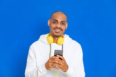 Mavi arka planda beyaz bir kazak giyen Afrikalı adam.