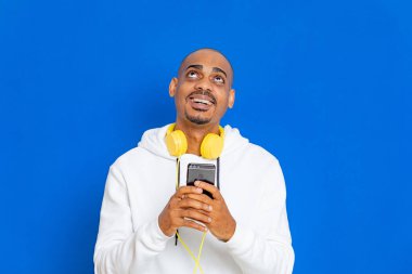 Mavi arka planda beyaz bir kazak giyen Afrikalı adam.