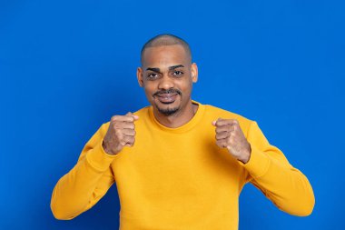 Mavi arka planda sarı formalı Afrikalı adam.