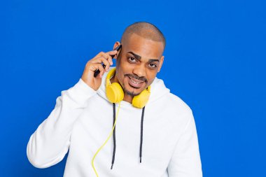 Mavi arka planda beyaz bir kazak giyen Afrikalı adam.