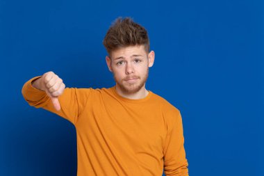 Mavi arka planda sarı tişörtlü çekici bir genç.