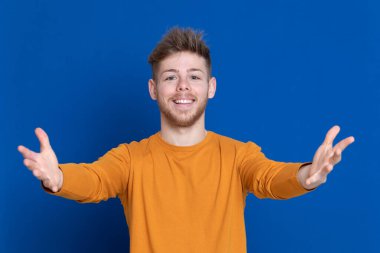 Mavi arka planda sarı tişörtlü çekici bir genç.