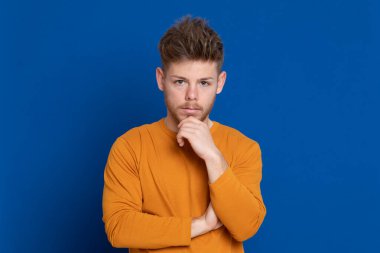 Mavi arka planda sarı tişörtlü çekici bir genç.