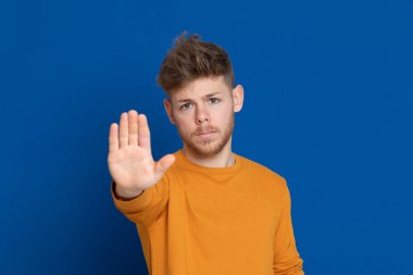 Mavi arka planda sarı tişörtlü çekici bir genç.