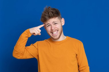 Mavi arka planda sarı tişörtlü çekici bir genç.