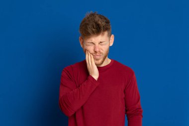 Mavi arka planda kırmızı tişörtlü çekici bir genç.