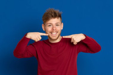 Mavi arka planda kırmızı tişörtlü çekici bir genç.