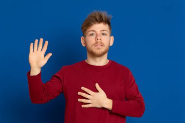 Mavi arka planda kırmızı tişörtlü çekici bir genç.