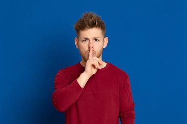 Mavi arka planda kırmızı tişörtlü çekici bir genç.