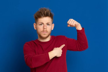 Mavi arka planda kırmızı tişörtlü çekici bir genç.