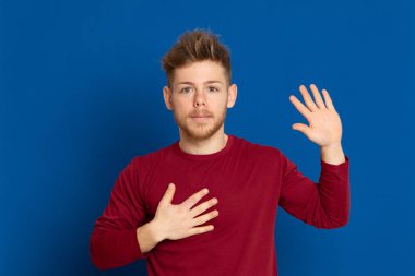 Mavi arka planda kırmızı tişörtlü çekici bir genç.