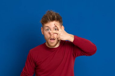 Mavi arka planda kırmızı tişörtlü çekici bir genç.