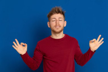 Mavi arka planda kırmızı tişörtlü çekici bir genç.