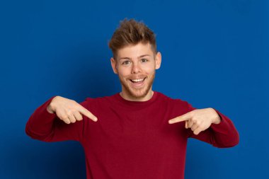 Mavi arka planda kırmızı tişörtlü çekici bir genç.