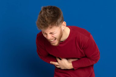 Mavi arka planda kırmızı tişörtlü çekici bir genç.