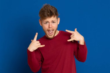 Mavi arka planda kırmızı tişörtlü çekici bir genç.