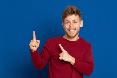 Mavi arka planda kırmızı tişörtlü çekici bir genç.