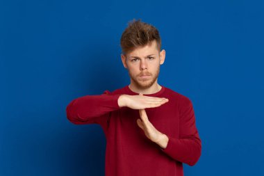 Mavi arka planda kırmızı tişörtlü çekici bir genç.