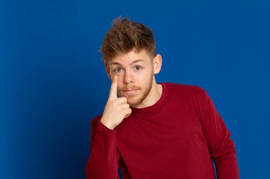 Mavi arka planda kırmızı tişörtlü çekici bir genç.