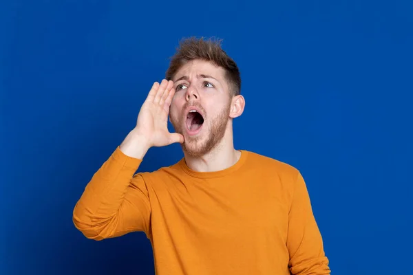 Aantrekkelijke Jongeman Met Een Geel Shirt Een Blauwe Achtergrond — Stockfoto