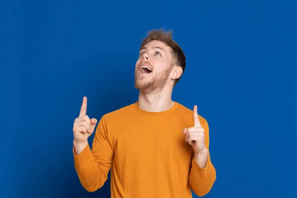 魅力的な若いです男とともにA黄色のTシャツ上の青の背景 — ストック写真