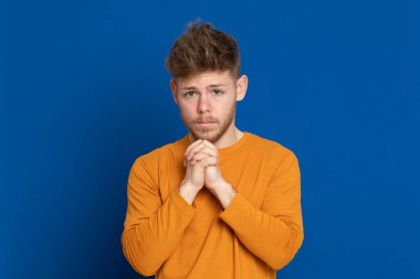 Mavi arka planda sarı tişörtlü çekici bir genç.