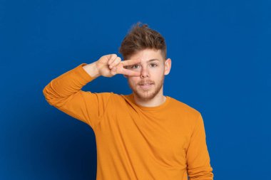 Mavi arka planda sarı tişörtlü çekici bir genç.