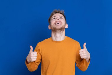 Mavi arka planda sarı tişörtlü çekici bir genç.