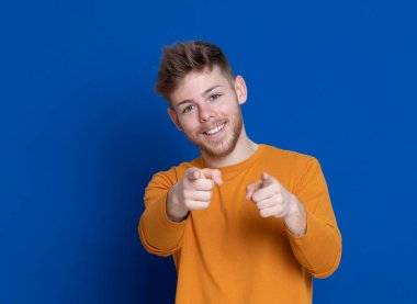 Mavi arka planda sarı tişörtlü çekici bir genç.