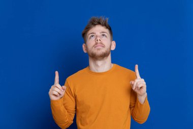 Mavi arka planda sarı tişörtlü çekici bir genç.