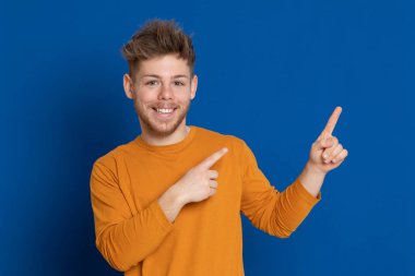 Mavi arka planda sarı tişörtlü çekici bir genç.