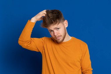 Mavi arka planda sarı tişörtlü çekici bir genç.