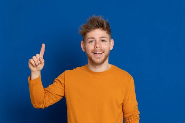 Mavi arka planda sarı tişörtlü çekici bir genç.