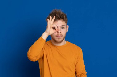 Mavi arka planda sarı tişörtlü çekici bir genç.