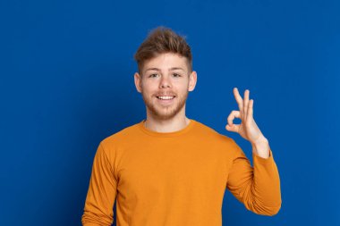 Mavi arka planda sarı tişörtlü çekici bir genç.