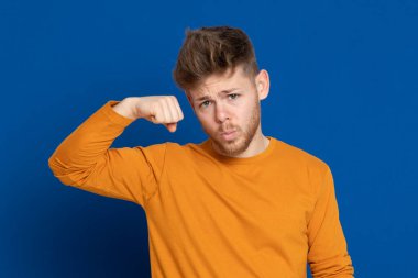 Mavi arka planda sarı tişörtlü çekici bir genç.