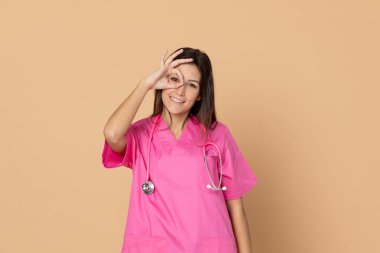 Sarı arka planda pembe üniformalı genç bir doktor.