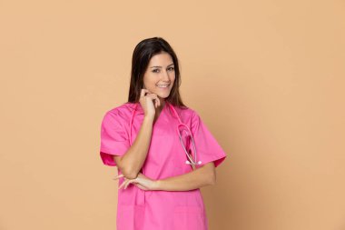 Sarı arka planda pembe üniformalı genç bir doktor.