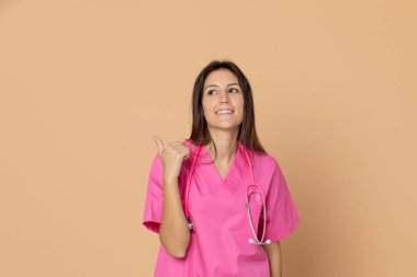 Sarı arka planda pembe üniformalı genç bir doktor.
