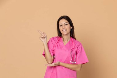 Sarı arka planda pembe üniformalı genç bir doktor.