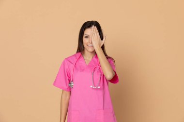 Sarı arka planda pembe üniformalı genç bir doktor.