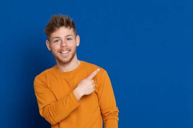 Mavi arka planda sarı tişörtlü çekici bir genç.