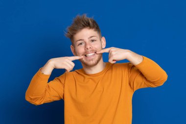 Mavi arka planda sarı tişörtlü çekici bir genç.