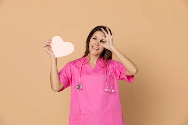 Sarı arka planda pembe üniformalı genç bir doktor.