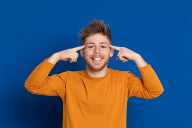 Mavi arka planda sarı tişörtlü çekici bir genç.