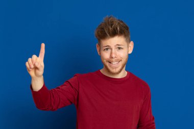 Mavi arka planda kırmızı tişörtlü çekici bir genç.