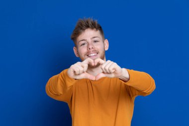 Mavi arka planda sarı tişörtlü çekici bir genç.