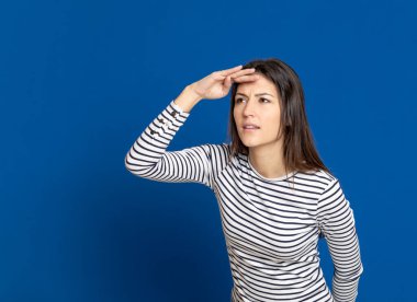 Mavi arka planda çizgili tişört giyen esmer genç bir kadın.