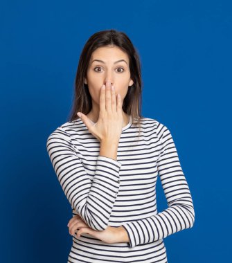 Mavi arka planda çizgili tişört giyen esmer genç bir kadın.